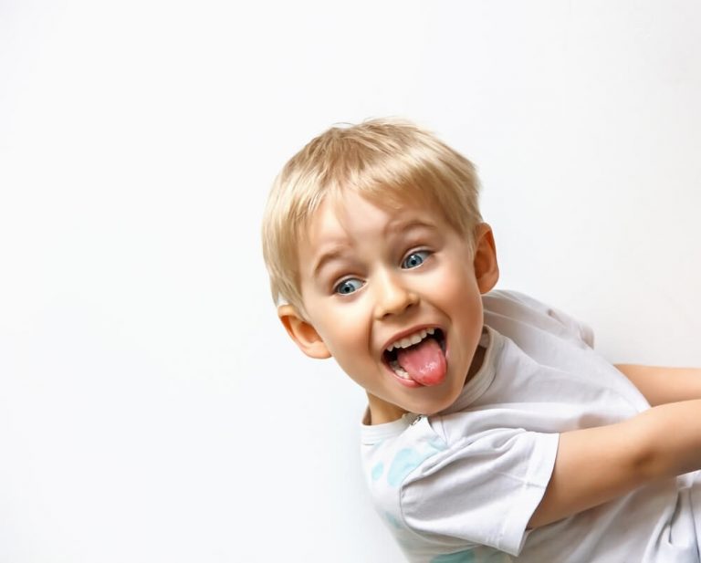 liten gutt smiler med tungen ut