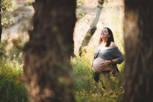 Gravid kvinne smiler i solen i parken
