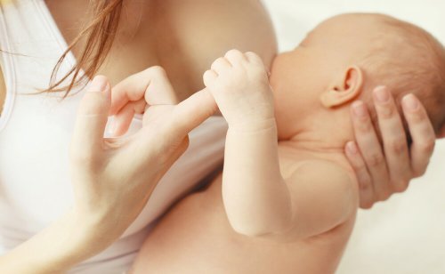 baby som ammer og griper tak i finger