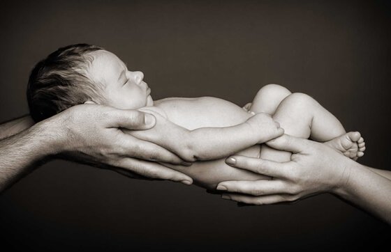 nyfødt baby blir holdt av førstegangsforeldre