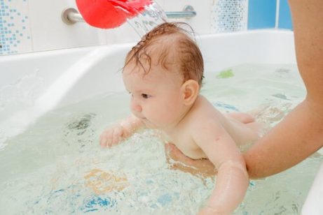 roe ned babyen med et bad