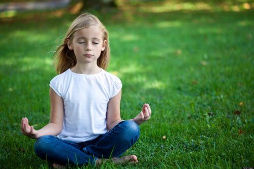 Ung jente mediterer på gresset