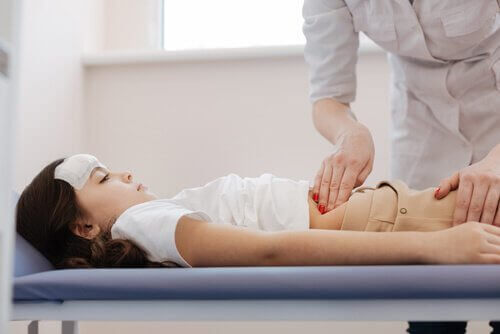 En voksen person sjekker magen til et barn.