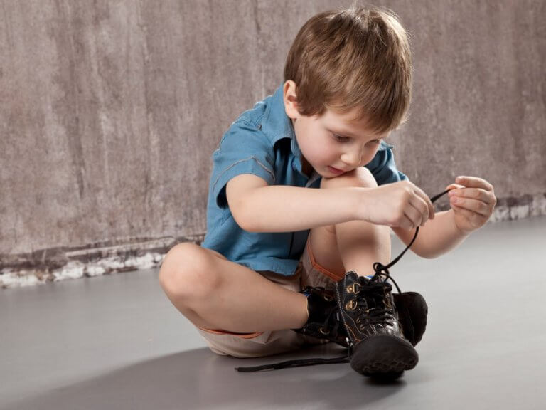 Liten gutt knyter skoene sine