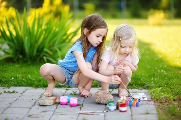 To barn som leker med maling ute.