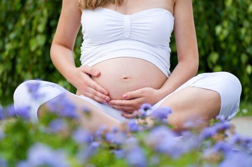 En gravid kvinne sitter i lotusstilling.