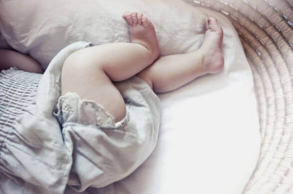 Bakdelen av en baby som ligger i en krybbe.