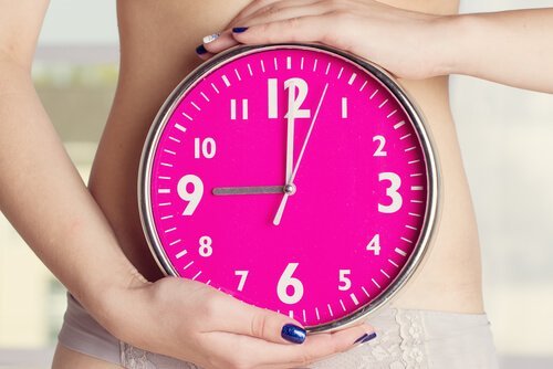 En kvinne som holder en klokke, et tegn på uregelmessig menstruasjon under amming