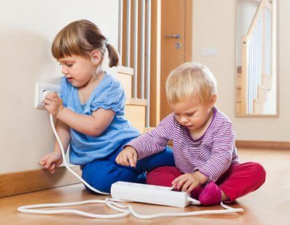 Barn som leker med stikkontakter, noe du burde unngå hvis du vil gjøre hjemmet babysikkert.