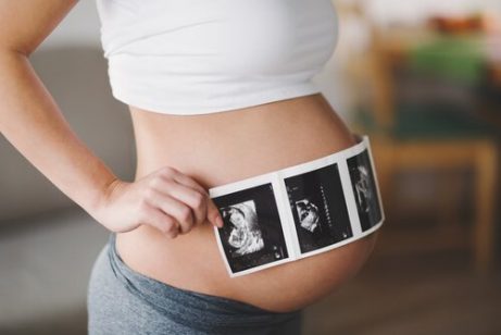 En kvinne holder ultralydbilder over sin gravide mage