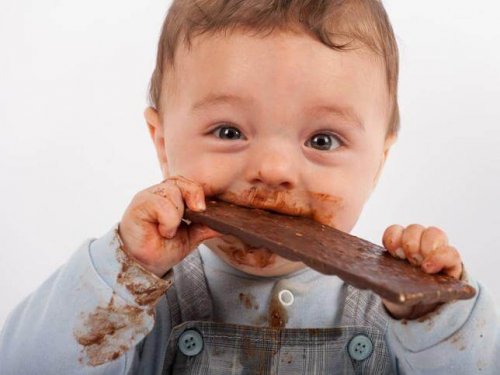 Liten baby spiser sjokolade.