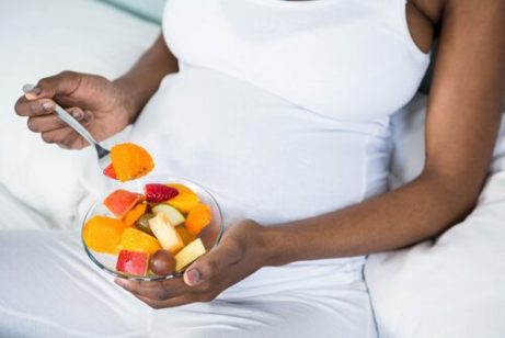 gravid kvinne som spiser en bolle med frukt