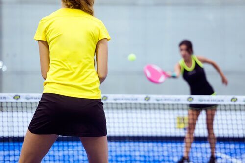 To jenter som spiller padeltennis på en bane.