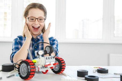 Ei jente som er fornøyd med en robot hun har bygget