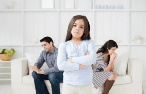 Et barn som står foran foreldrene sine og ser bestemt ut.