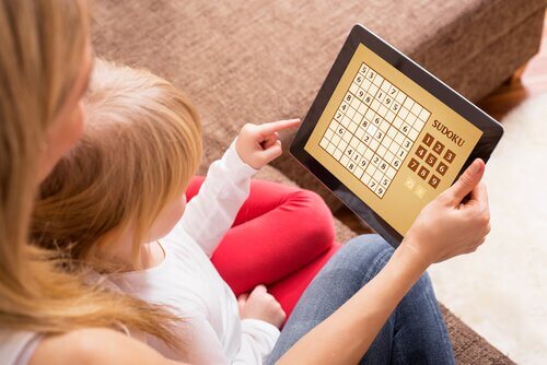 Mor og barn som sitter med et nettbrett og spiller sudoku