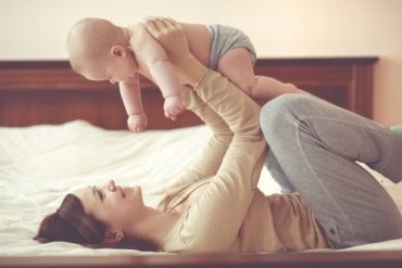 En mor som leker med babyen sin i sengen