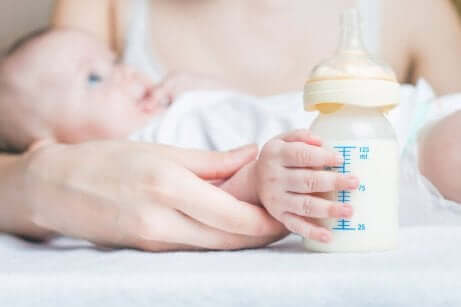 En baby som ligger på armen til moren sin og får flaske