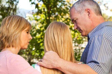 En familie som holder rundt tenåringsdatteren sin