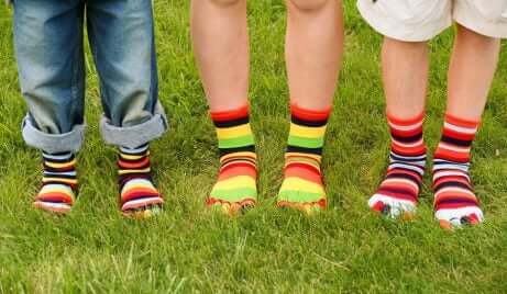 Føttene til tre barn med fargerike sokker på
