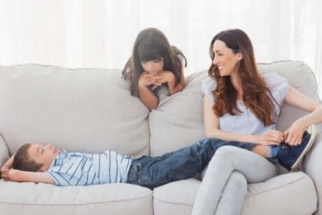 En mor som sitter i sofaen med sine to barn