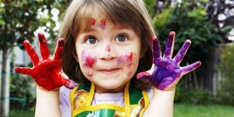 Et barn som har maling på hendene og i ansiktet