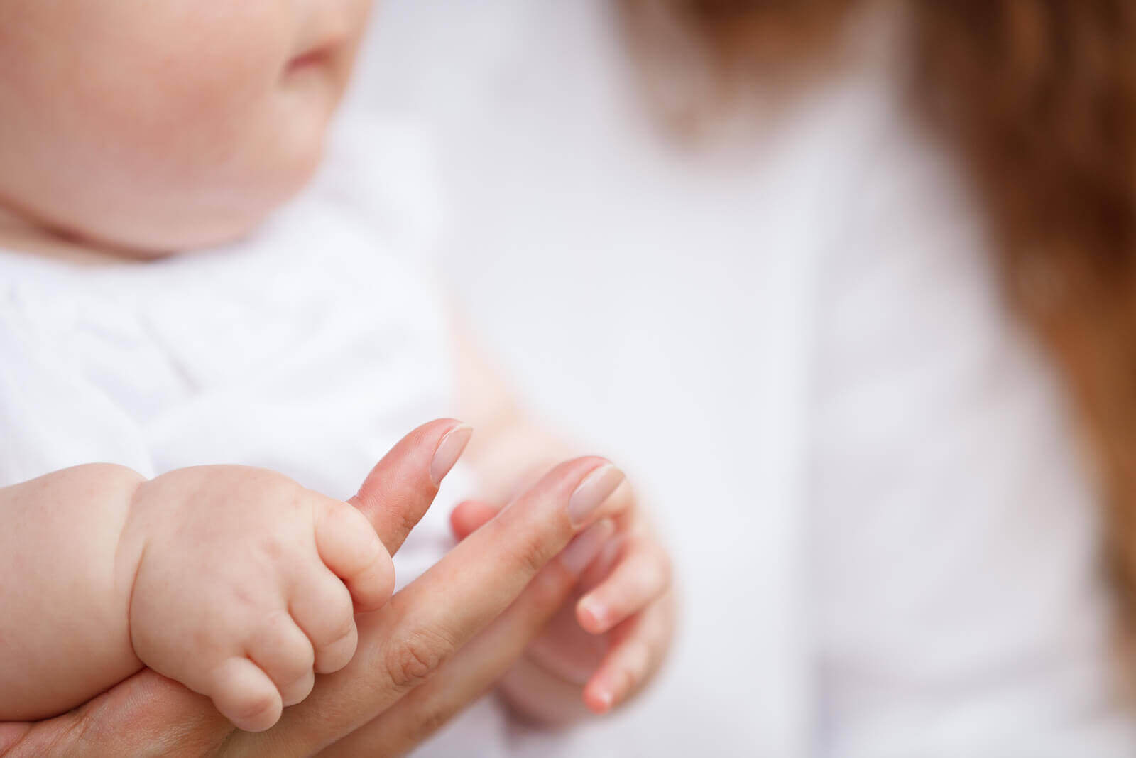 En baby som holder morens finger
