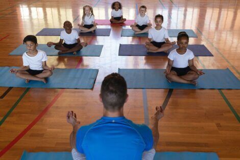 Barn som praktiserer yoga i en gymsal.