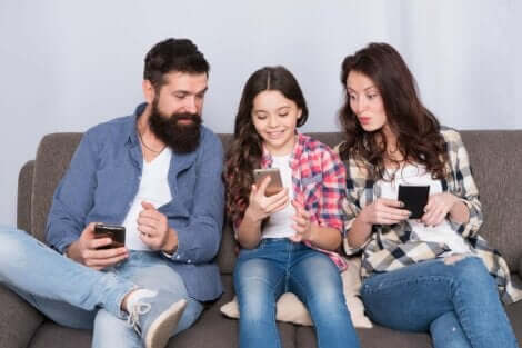En familie som sitter i sofaen med hver sin telefon