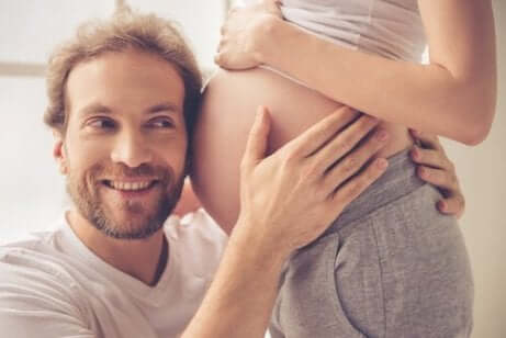 En mann som lytter til magen til en gravid kvinne