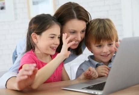 En mor med sine to barn foran en dataskjerm