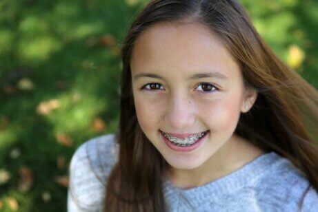 Jente med tannregulering som smiler.