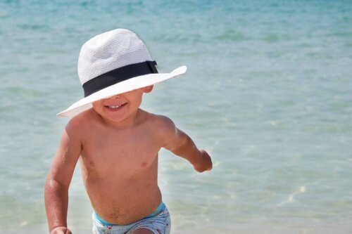 Et barn med solhatt på stranden